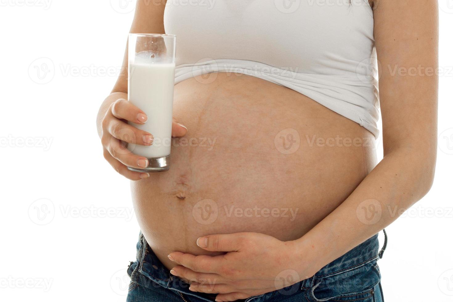 pregnant woman posing with glass of milk isolated on white background photo