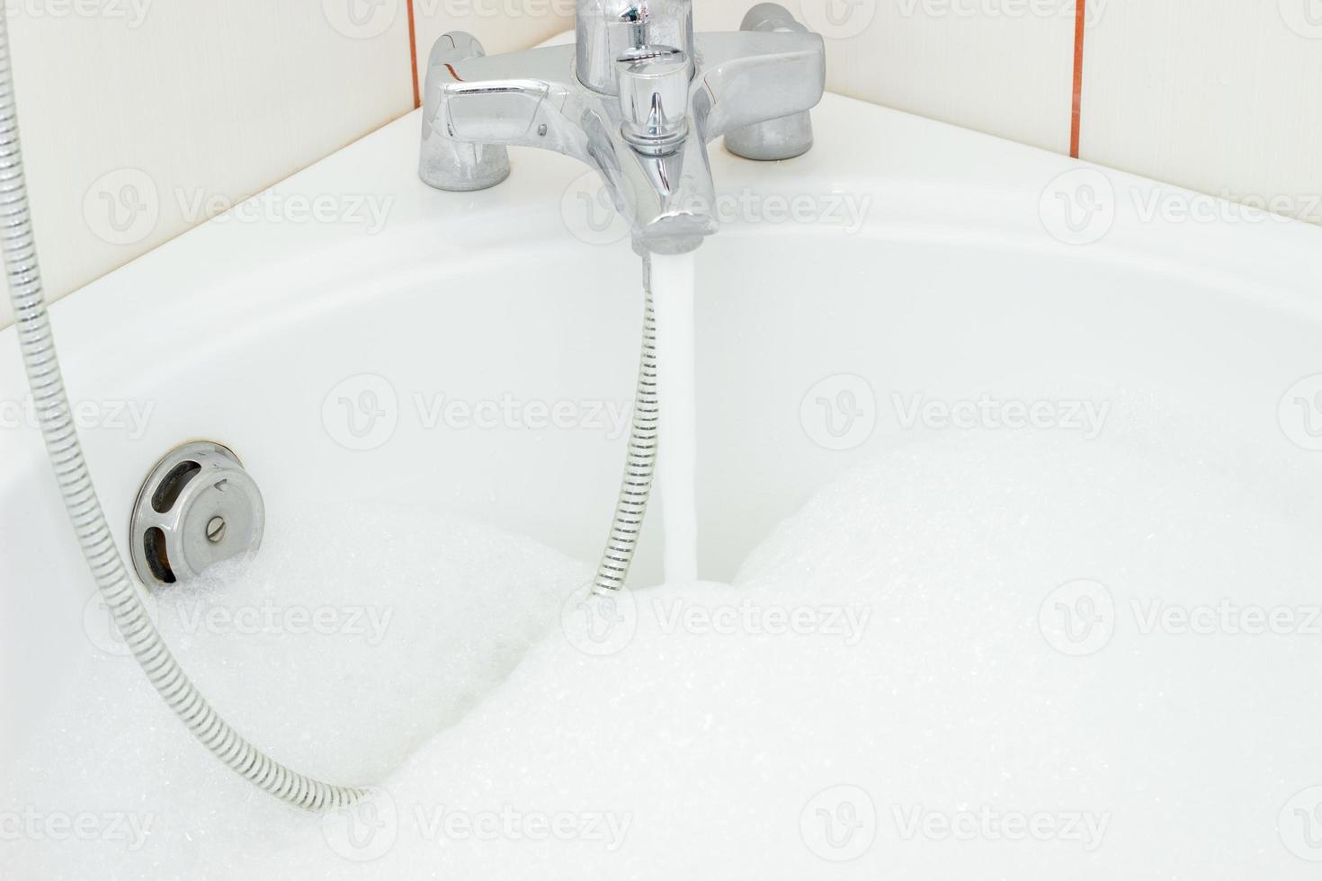el agua que sale del grifo del baño con espuma foto