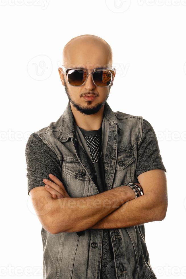 Serious unshaved man in sunglasses looking and posing on camera photo