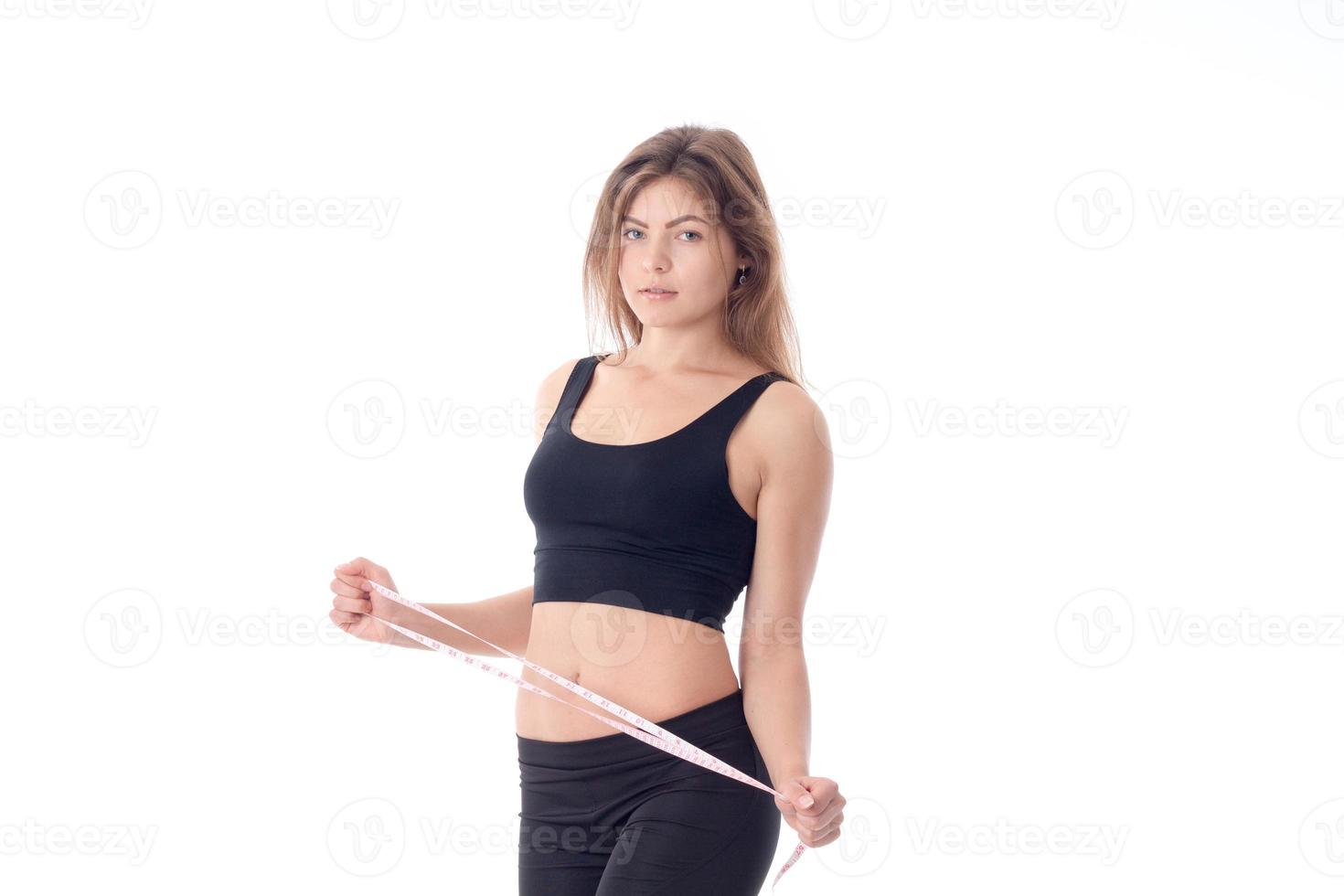 slender girl in black tights and  top side which is holding  tape measure photo