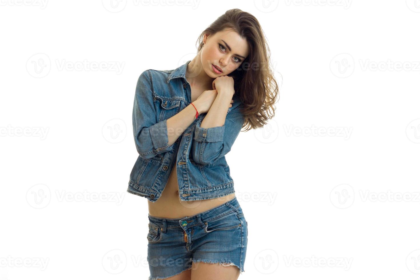 young beautiful girl in denim shorts and a jacket keeps your hands near your face and looks straight photo