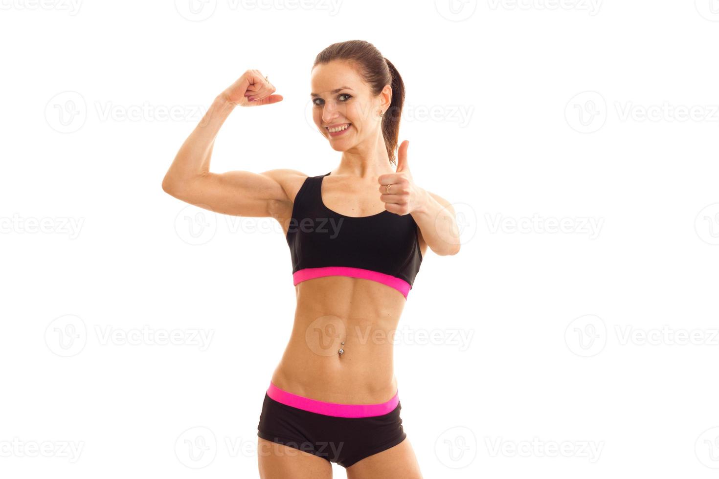 young smiling girl with press on her stomach in the sports top shows muscle on hand photo