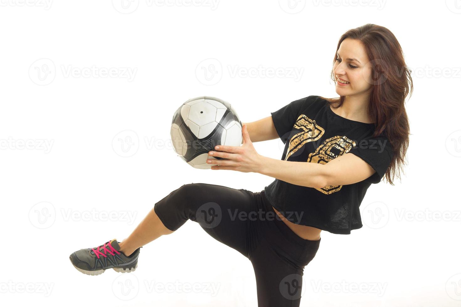 young cheerful sportswoman in black kicks a soccer ball kicked photo