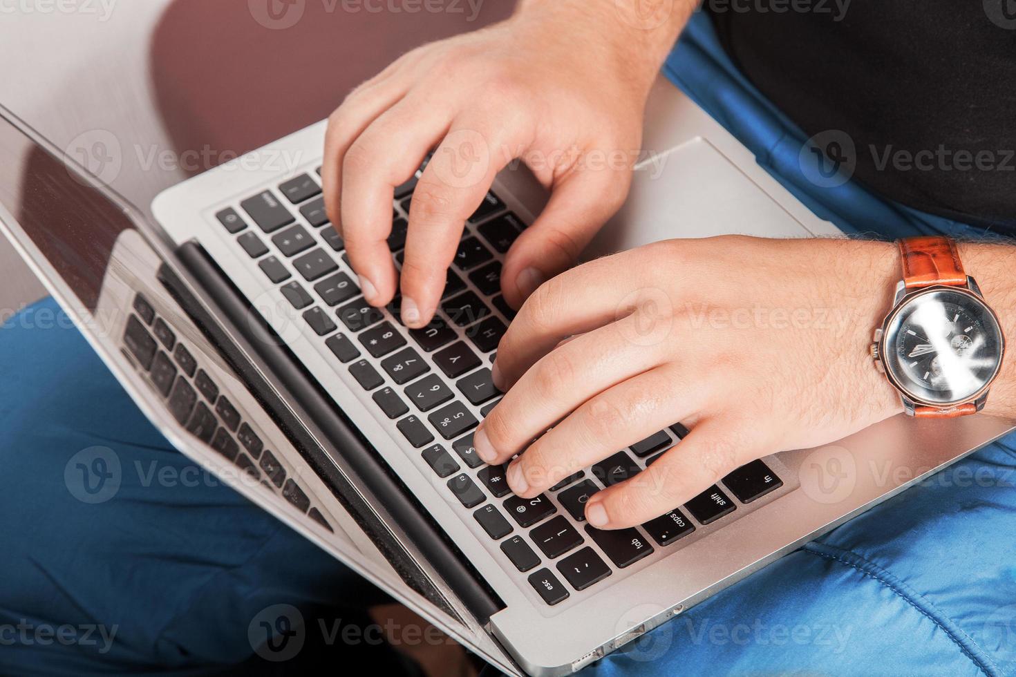 man in casual clothing typing on laptop photo