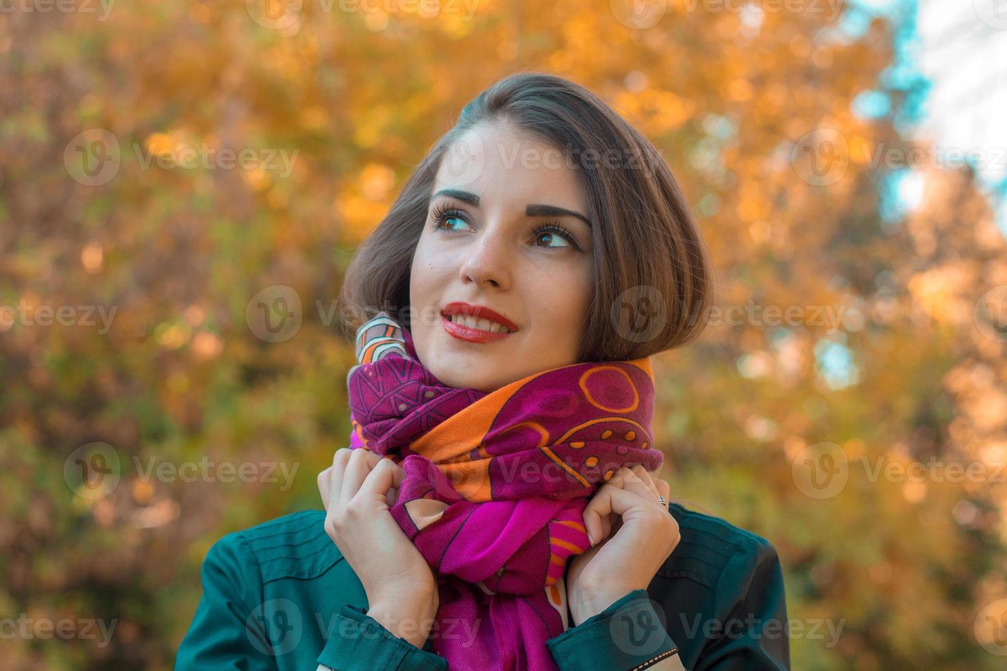 sweet girl stands on the street looks away and keeps hands scarf close-up photo