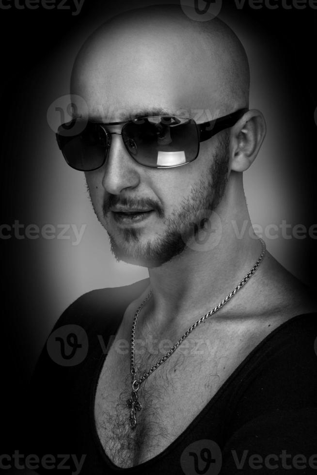 Black and white of hairless male in sunglasses looking at camera photo