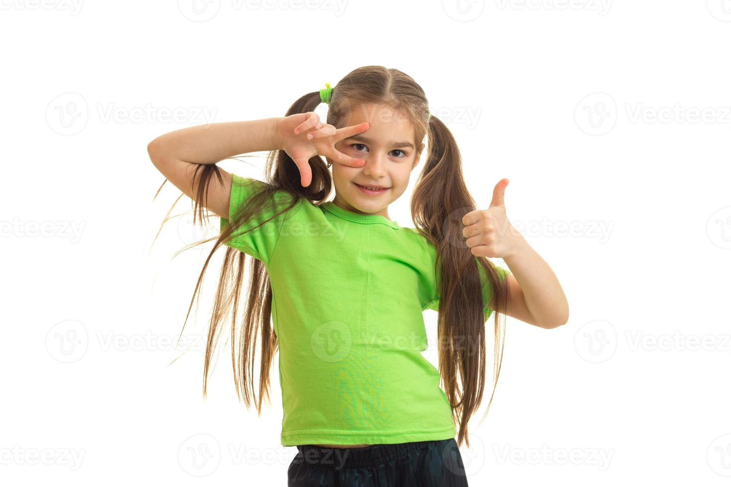 funny little girl showing thumbs up and smiling on camera photo