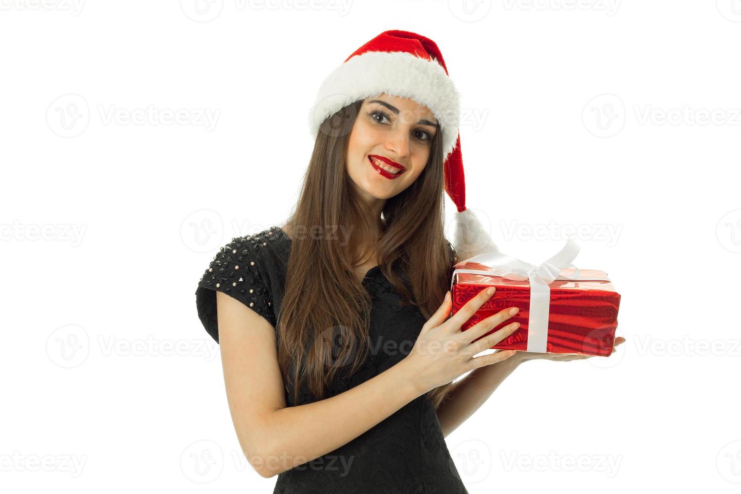 niña sonriente en sombrero de santa con regalo rojo foto