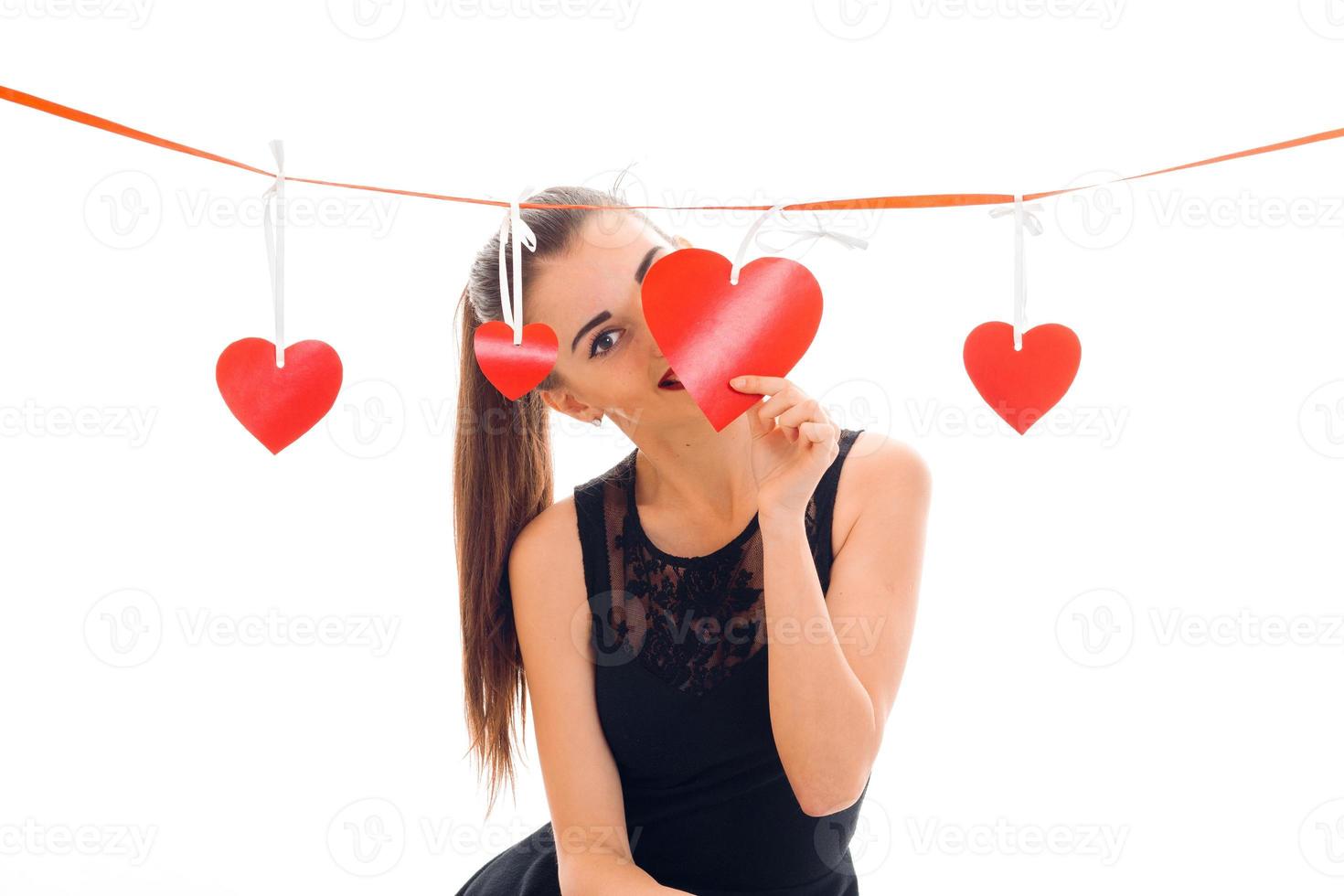 a young girl in a black dress with Red Ribbon stands near hearts photo