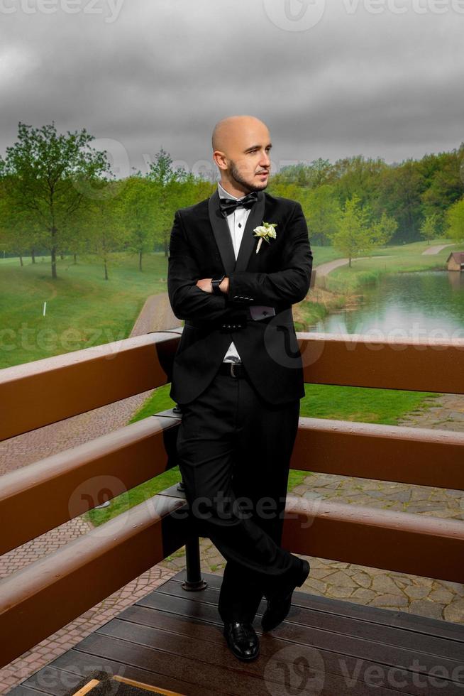 stylish young bridegroom posing and looking away photo