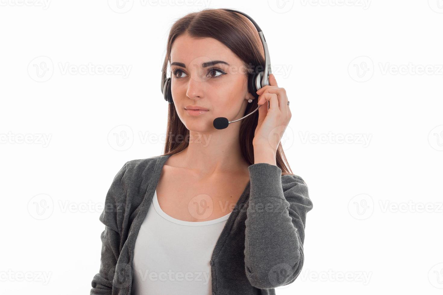 Atractiva joven chica de la oficina del centro de llamadas con auriculares y micrófono posando aislada de fondo blanco foto