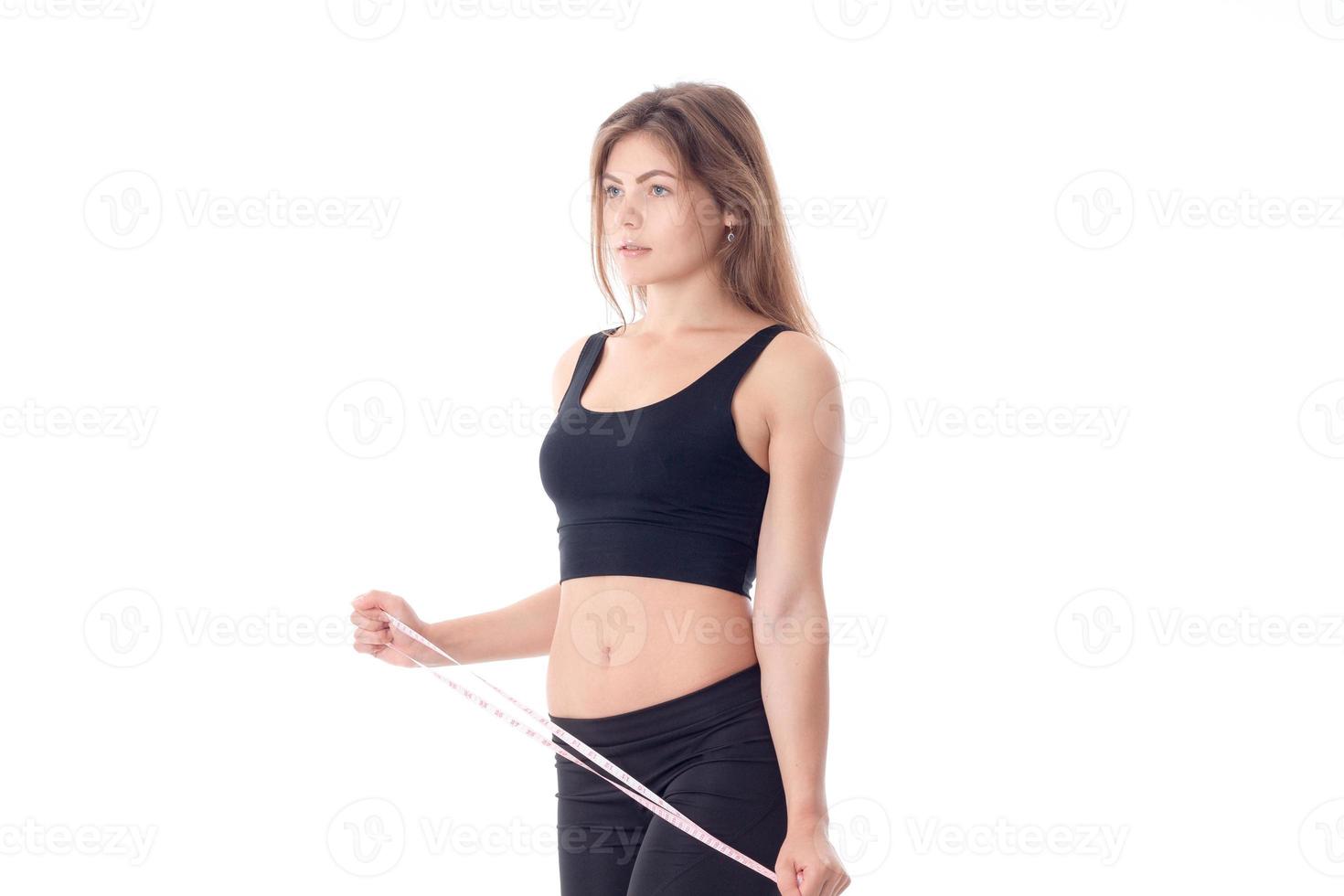 serious slender girl standing sideways which holds the measuring tape photo