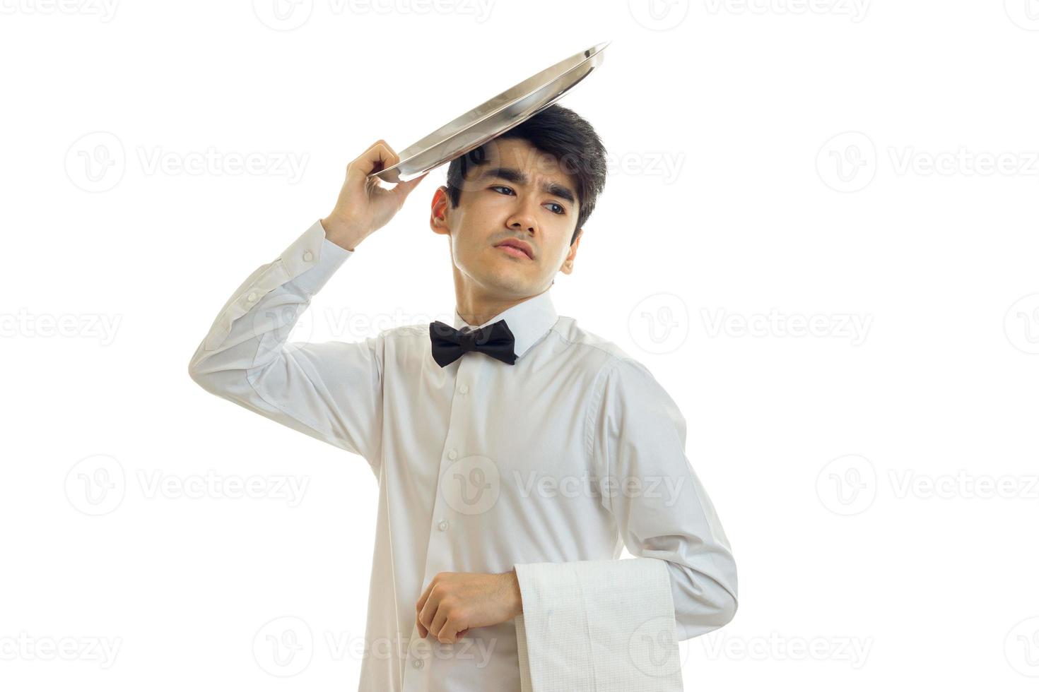 handsome young waiter got tired and put on the head of an empty dish podnom close-up photo