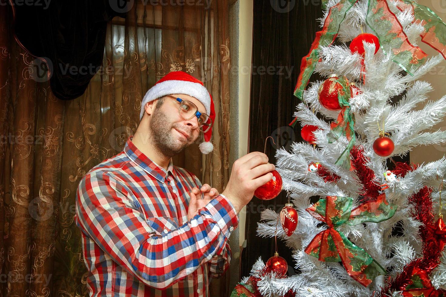 Nerd in santa hat decorate christmas tree photo