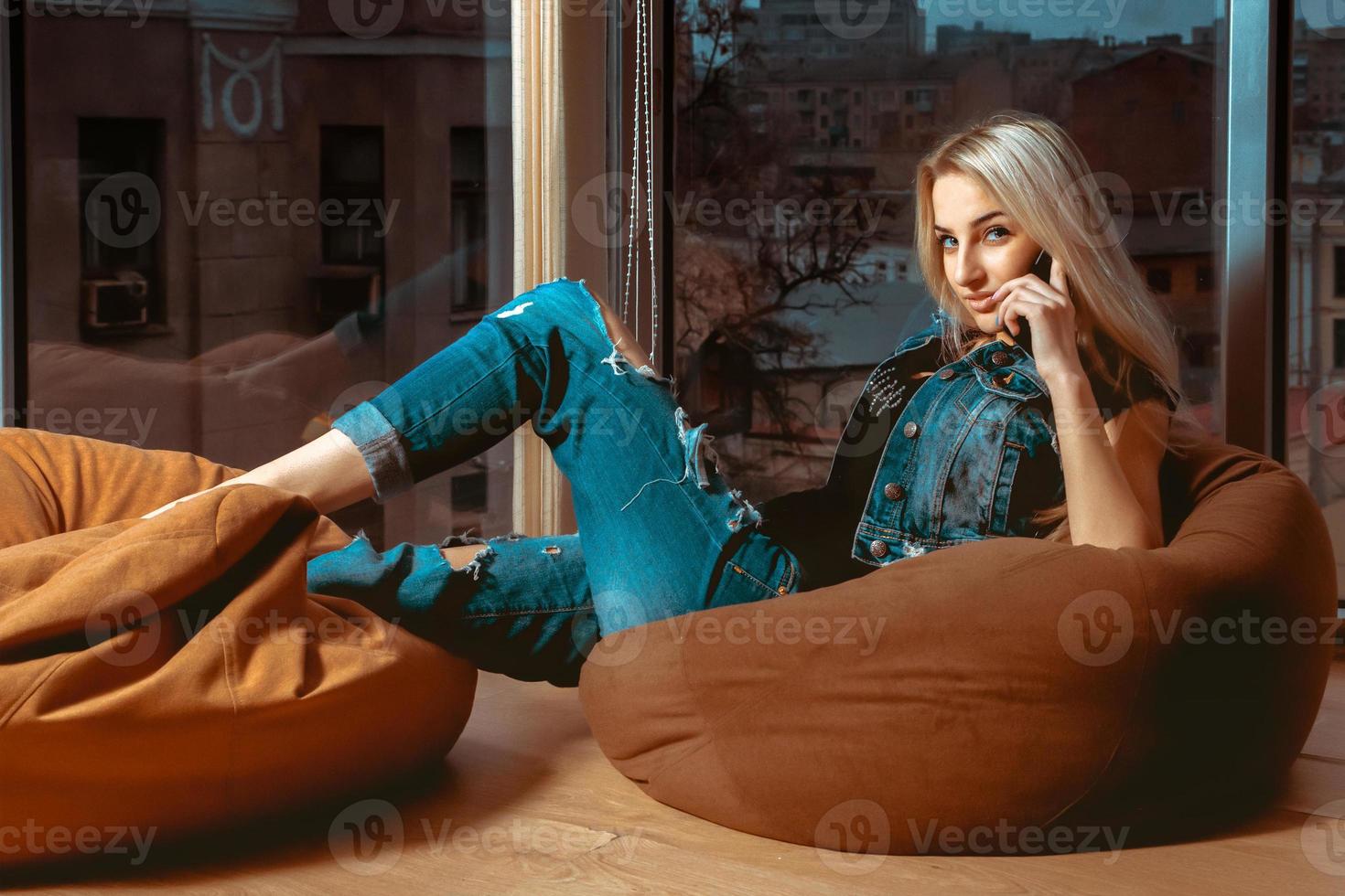 Fashion model posing on couch with mobile phone in hand and looking at the camera photo