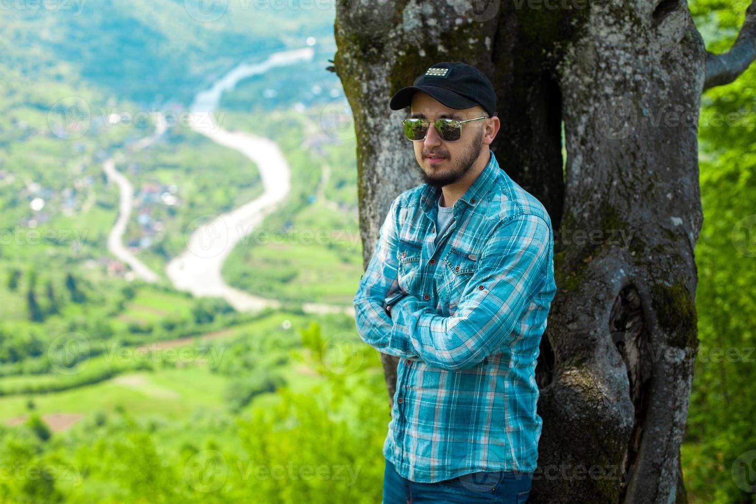 man in sunglasses posing with mountains view photo