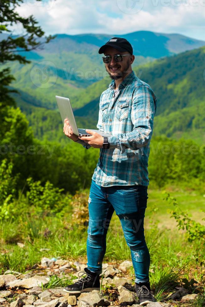 man working on laptop in the mountains photo
