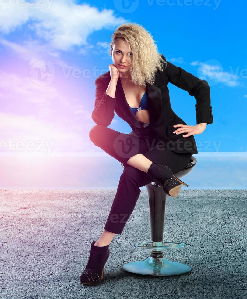 young blonde business lady with blue eyes sits on chair photo