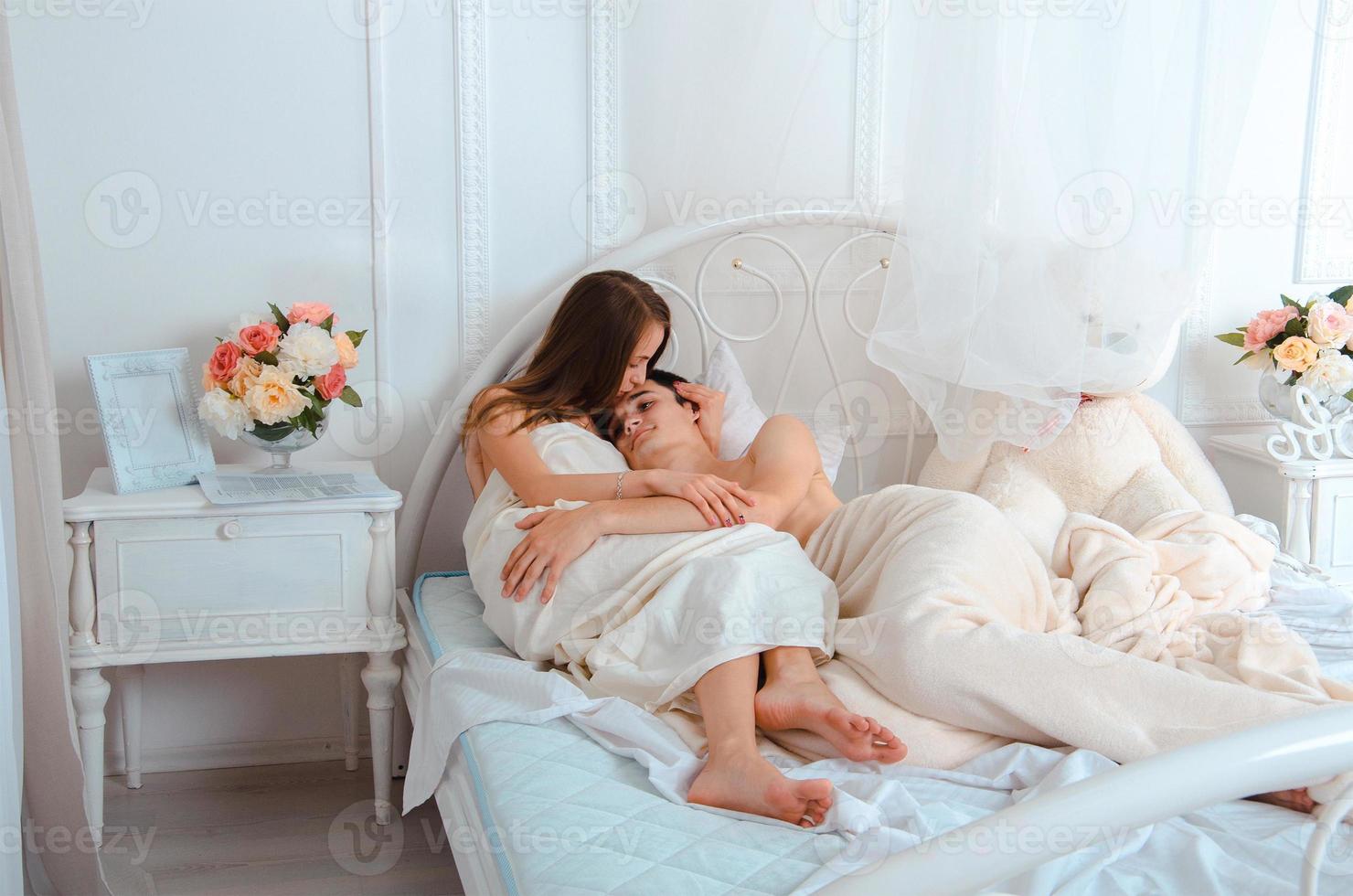 young lovers hugging in white bed photo