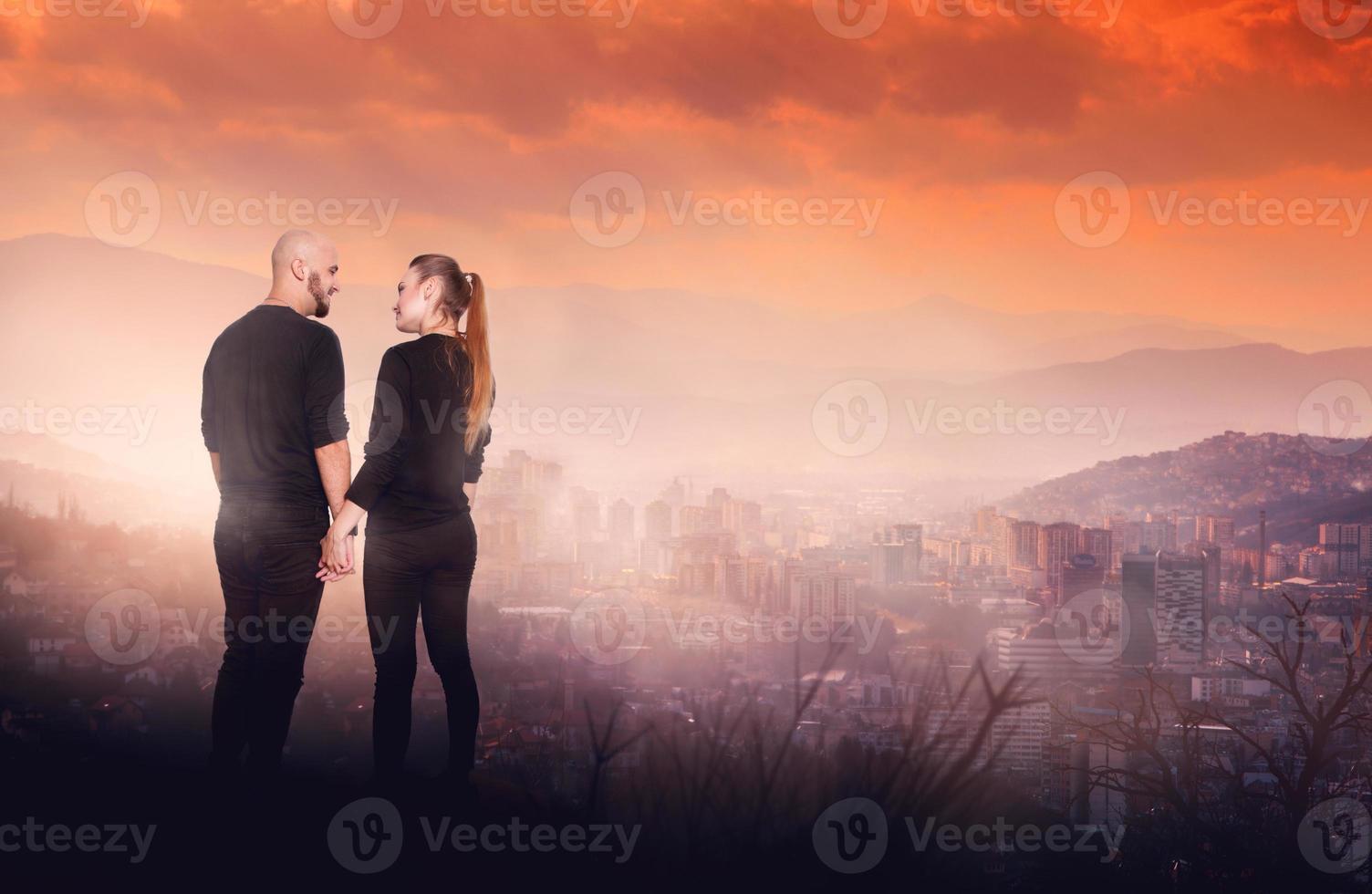 pareja en una colina alta con vista a la ciudad foto