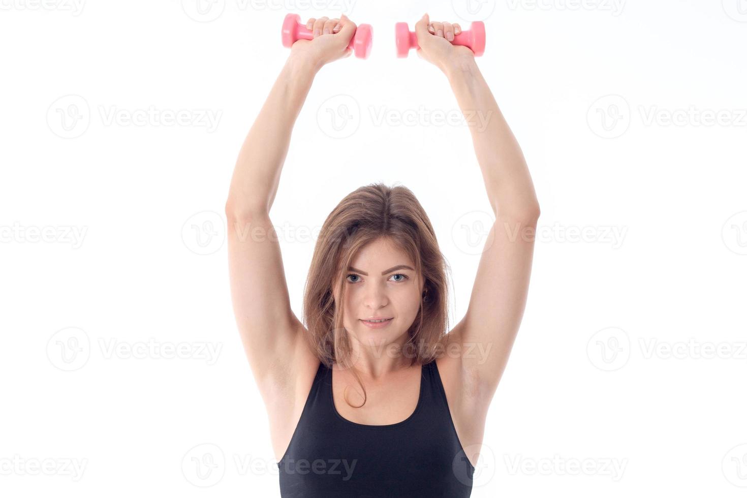 athletic woman is holding up two hands with dumbbells photo