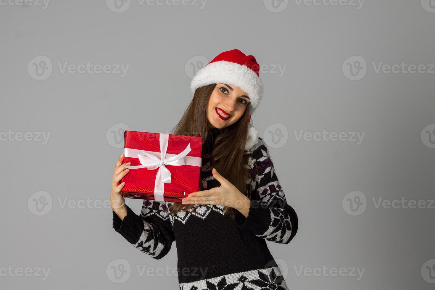 mujer en suéter cálido y sombrero de santa con regalo rojo foto