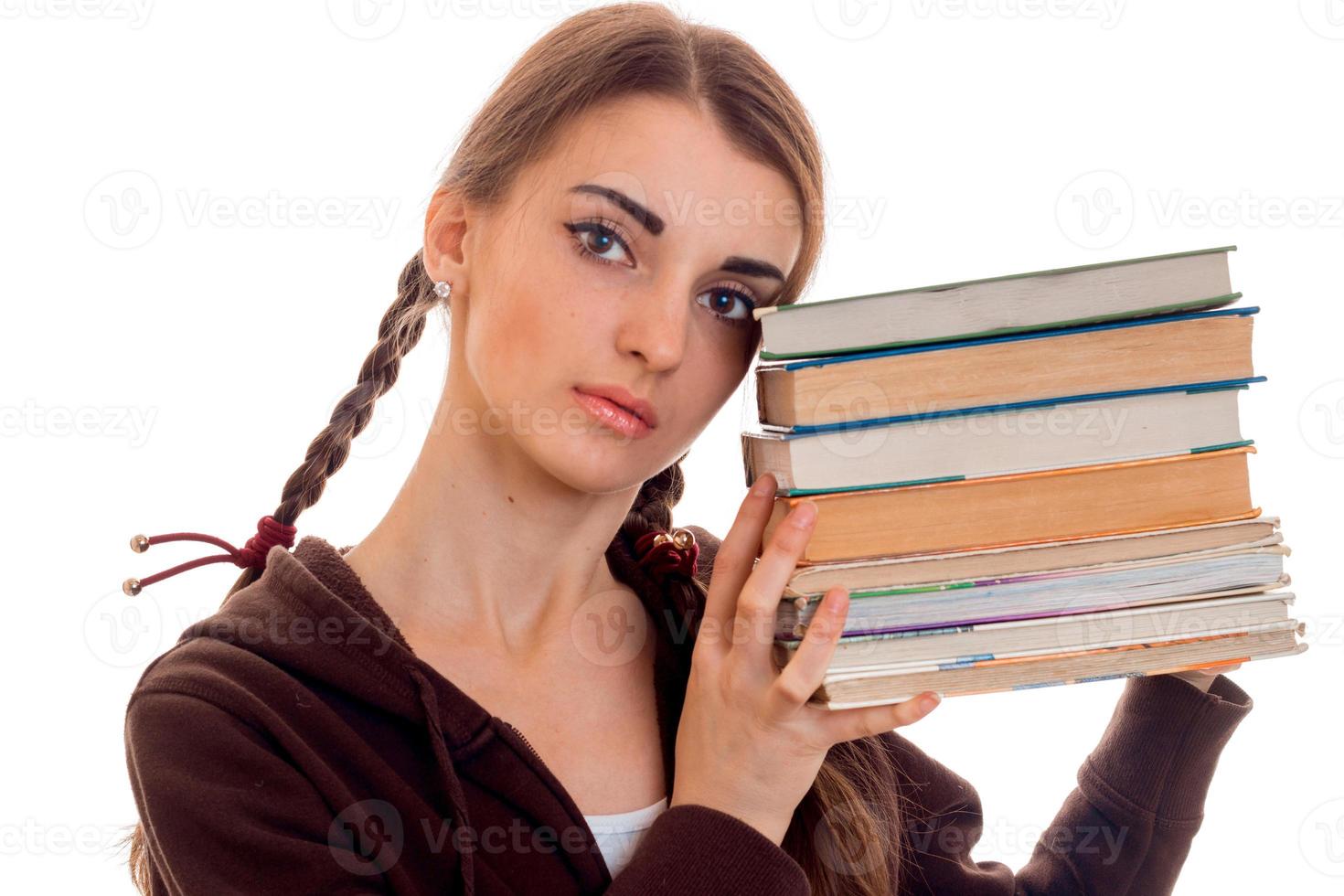 close up portrait of young attractive student girl in brown sport clothes with a lot of books in hands isolated on white background photo