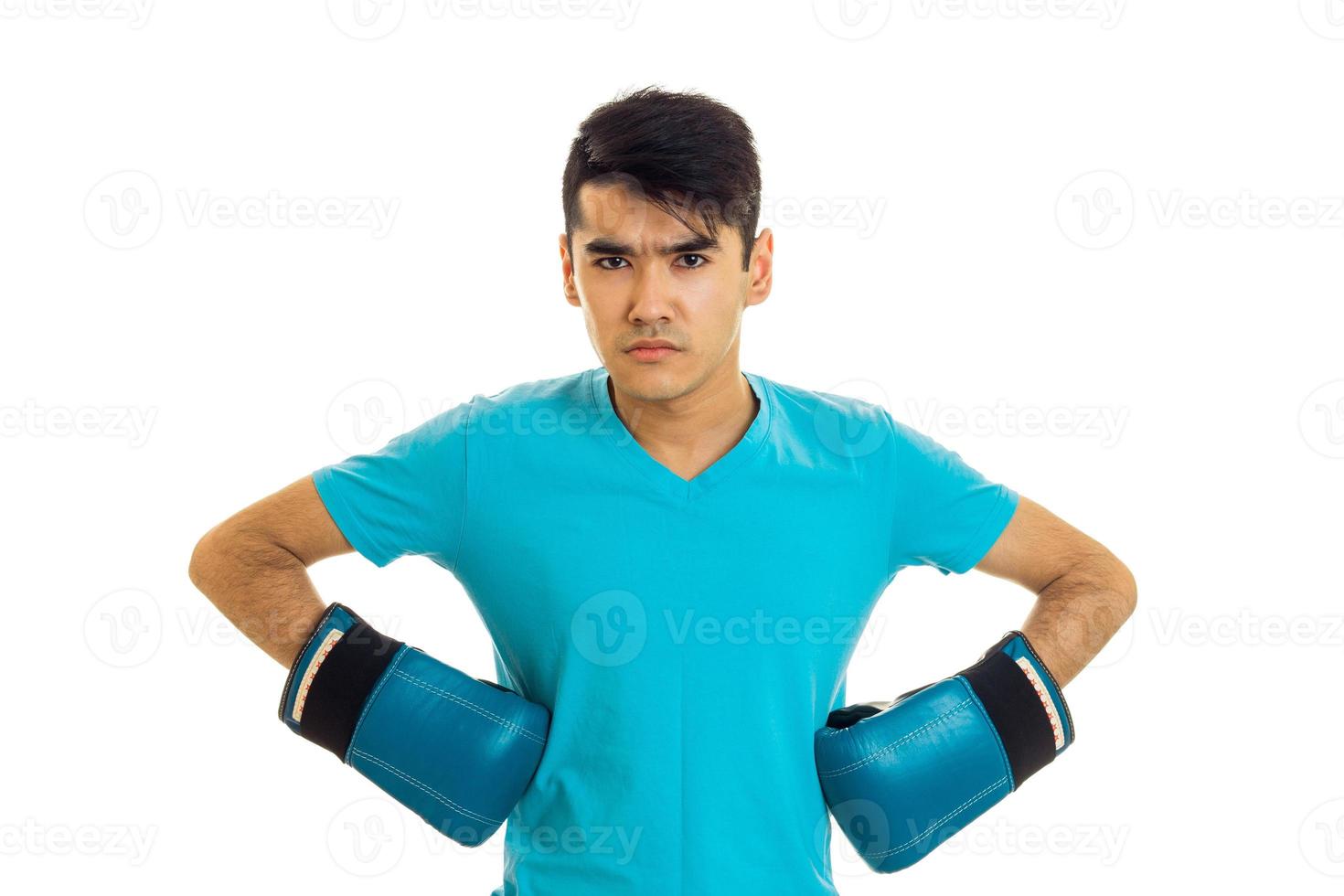 hombre serio posando con camisa azul y guantes de boxeo aislados en fondo blanco en el estudio foto