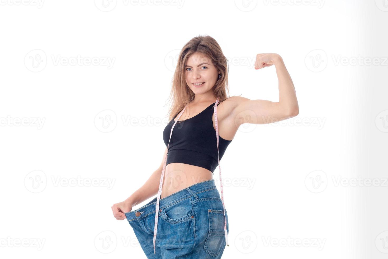 Slim young girl in big wide pants shows muscle on hand isolated  white background photo