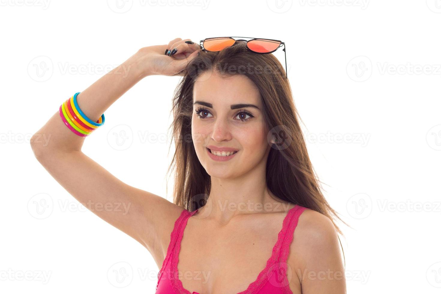 retrato de una joven encantadora con gafas de sol mirando hacia otro lado y sonriendo aislada de fondo blanco foto