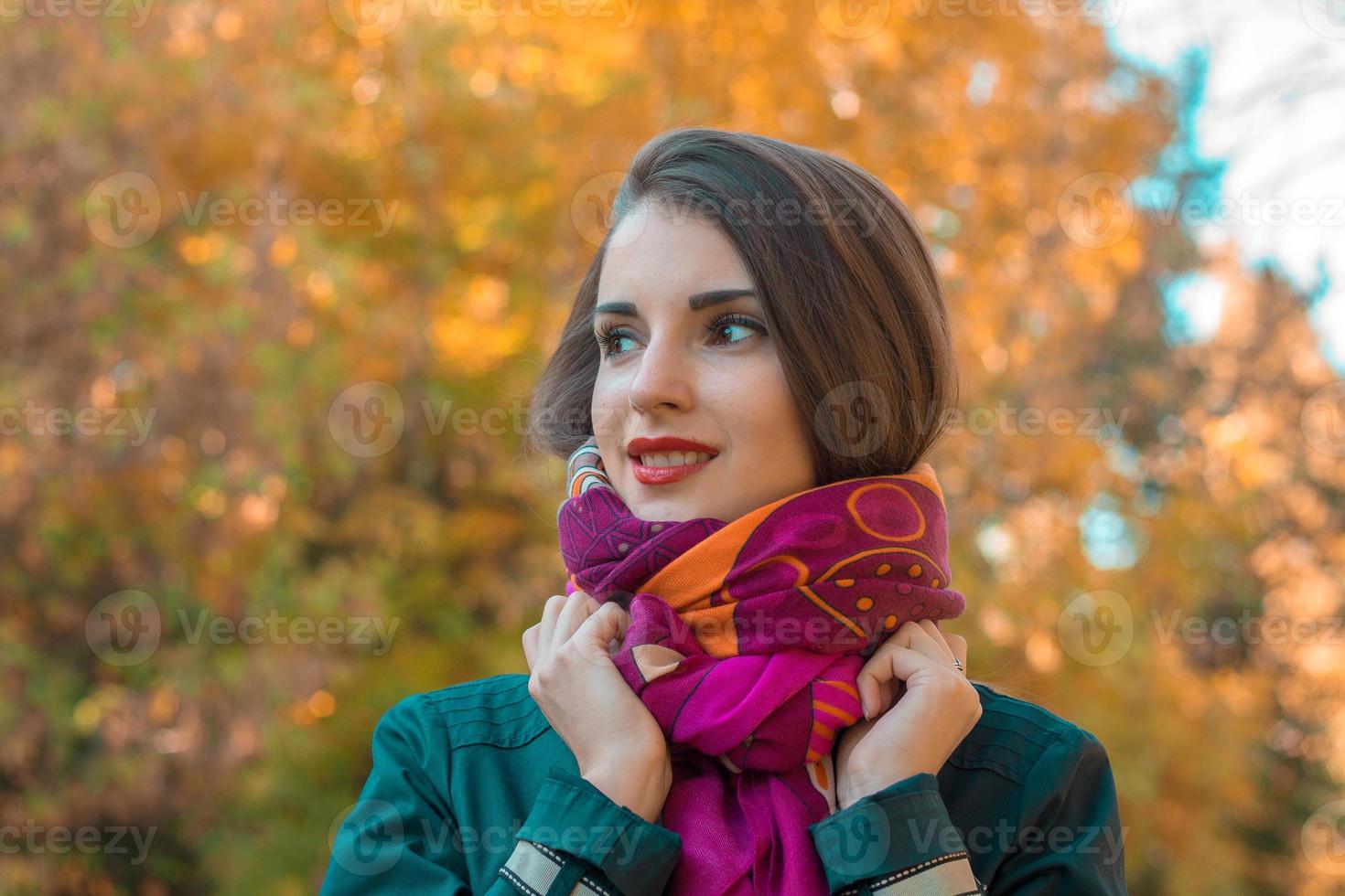 linda chica se para en el parque mira hacia otro lado y mantiene las manos bufanda foto