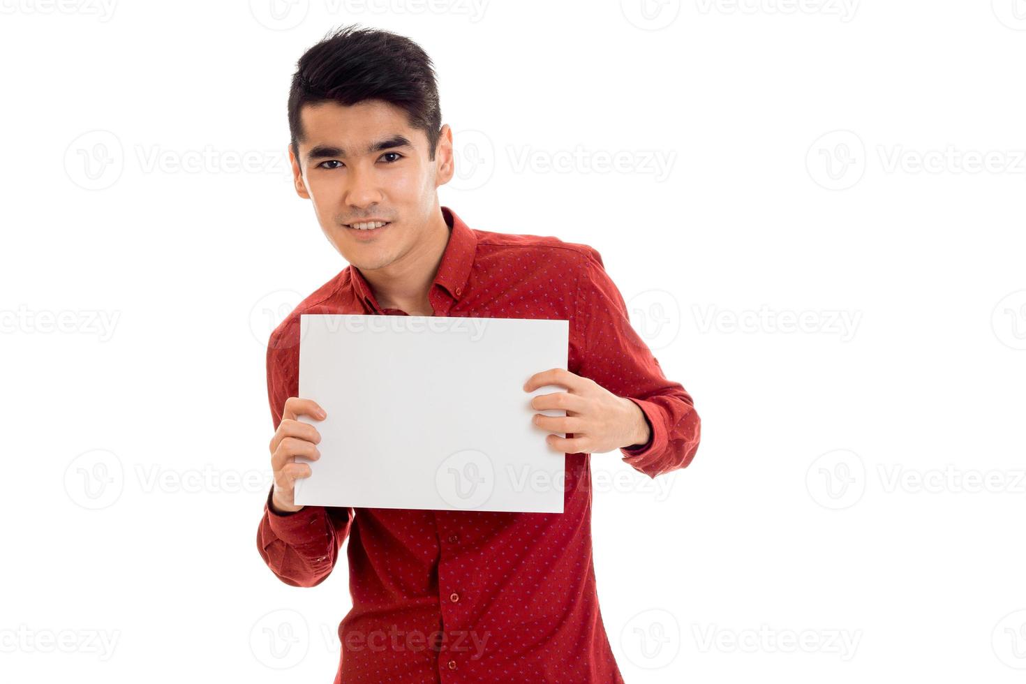 cheerful young guy in red shirt with empty placard in hands posing isolated on white background photo