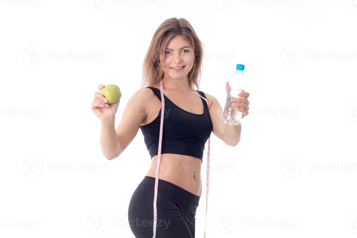 slim girl smiling and stretched out both hands forward shows a fruit   bottle of water photo