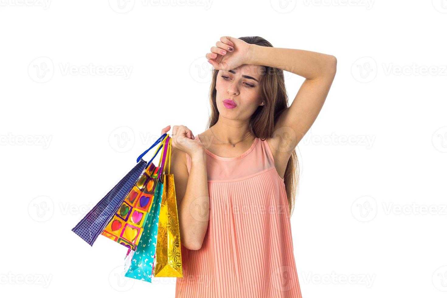 young girl holding a different packages of stores and second hand keeps near the head isolated on white background photo