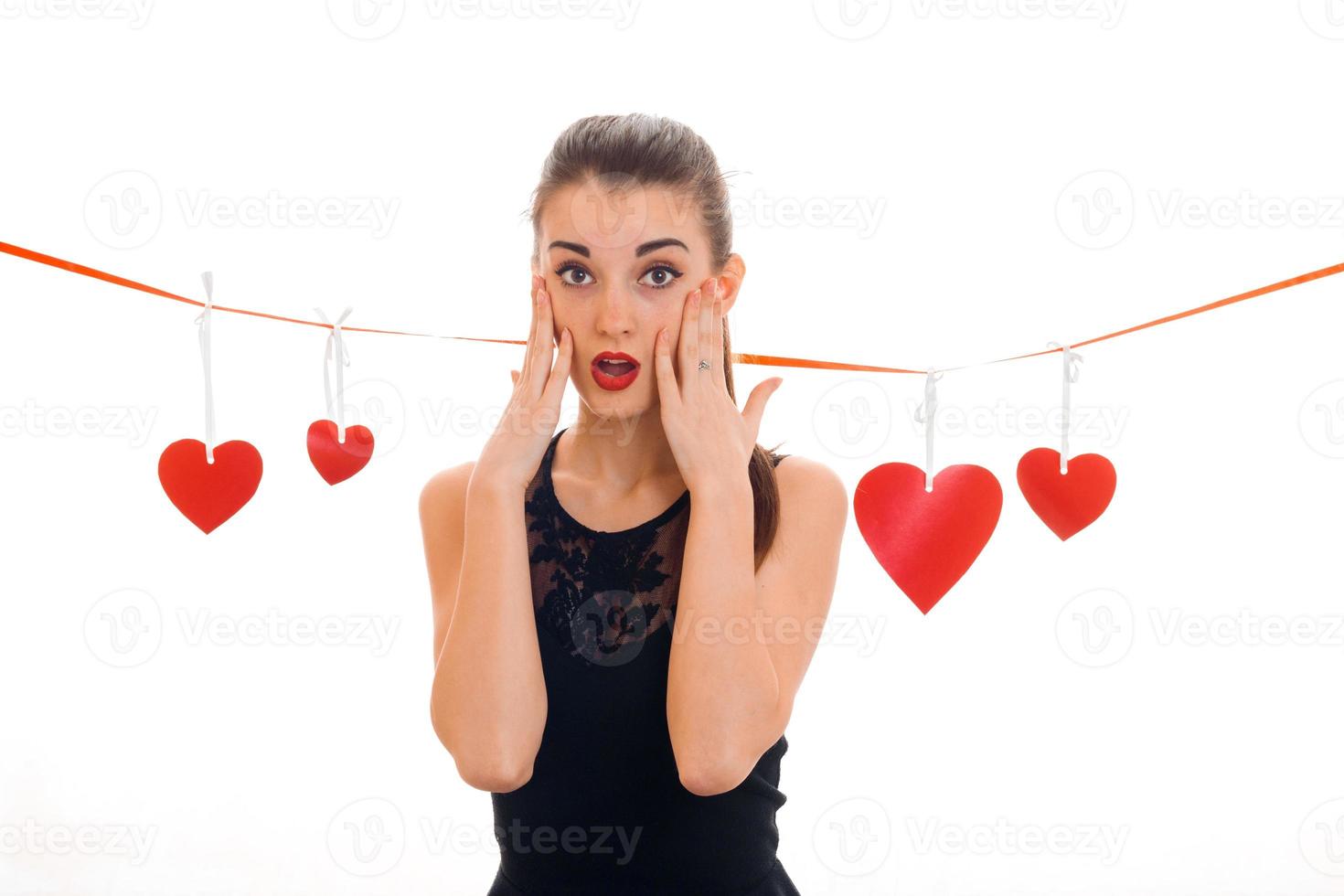 Beautiful young brunette woman with red heart in hands posing isolated on white background. Saint Valentine's day concept. Love concept. photo