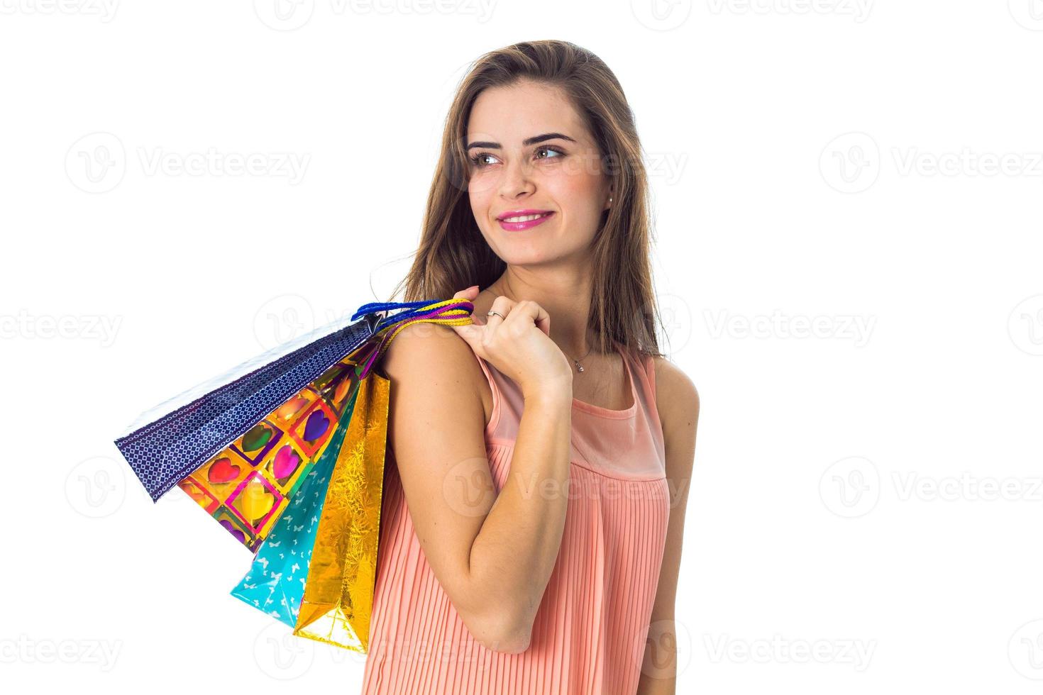 linda chica mira hacia otro lado y mantiene las bolsas de hombro aisladas en fondo blanco foto