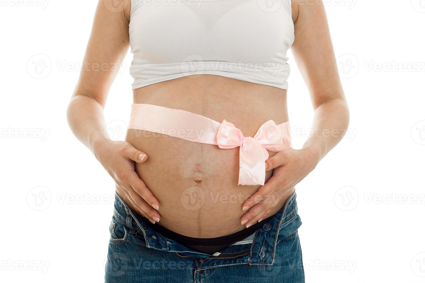 pregnant woman posing with pink tape on her belly isolated on white background photo
