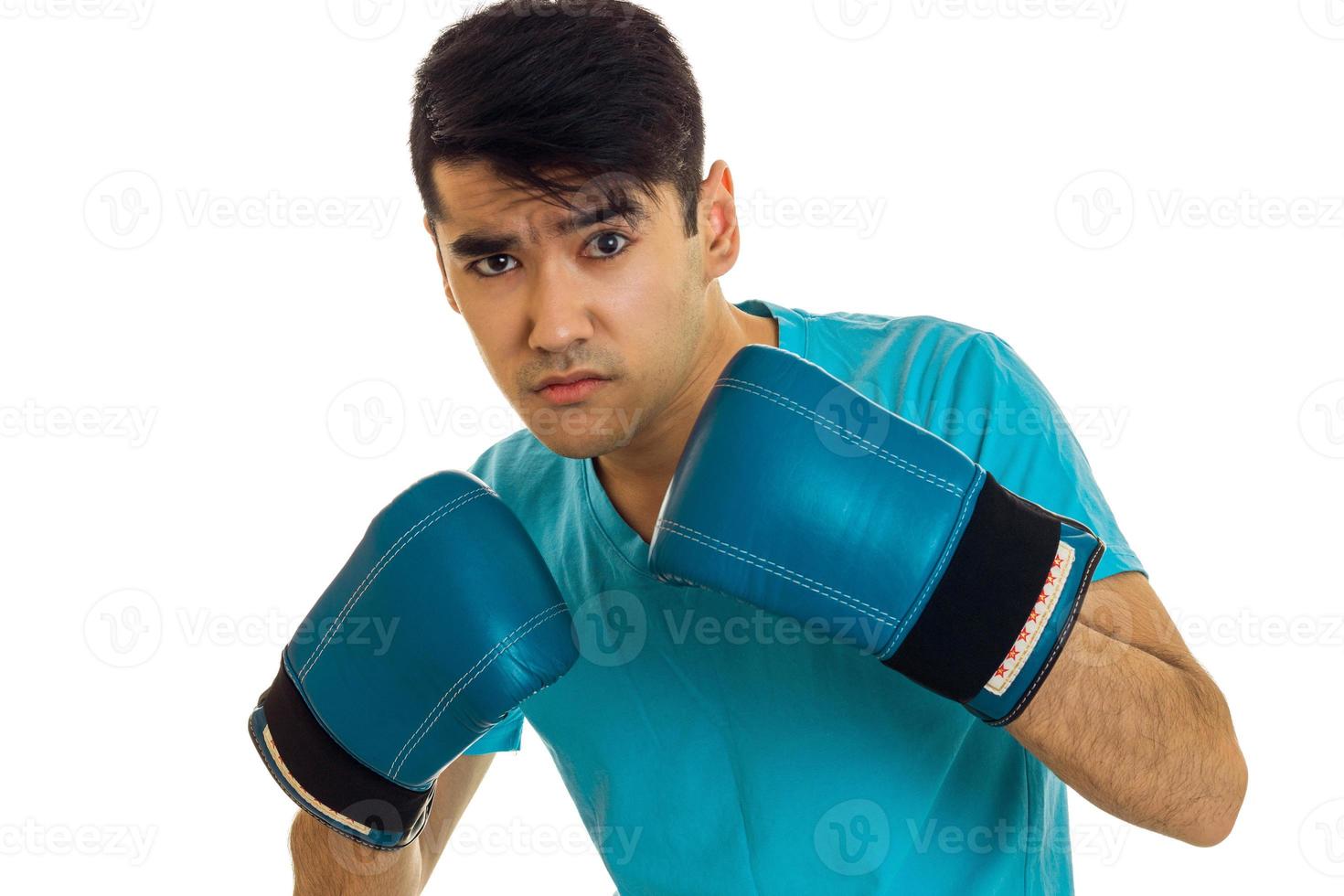 joven hombre concentrado en camisa azul practicando boxeo en guantes aislado sobre fondo blanco foto