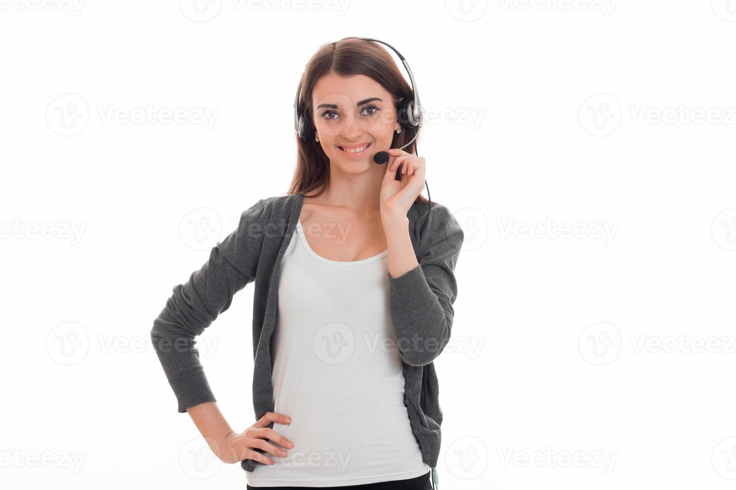 alegre joven morenita llamada oficinista mujer con auriculares y micrófono sonriendo a la cámara aislada en el fondo blanco foto