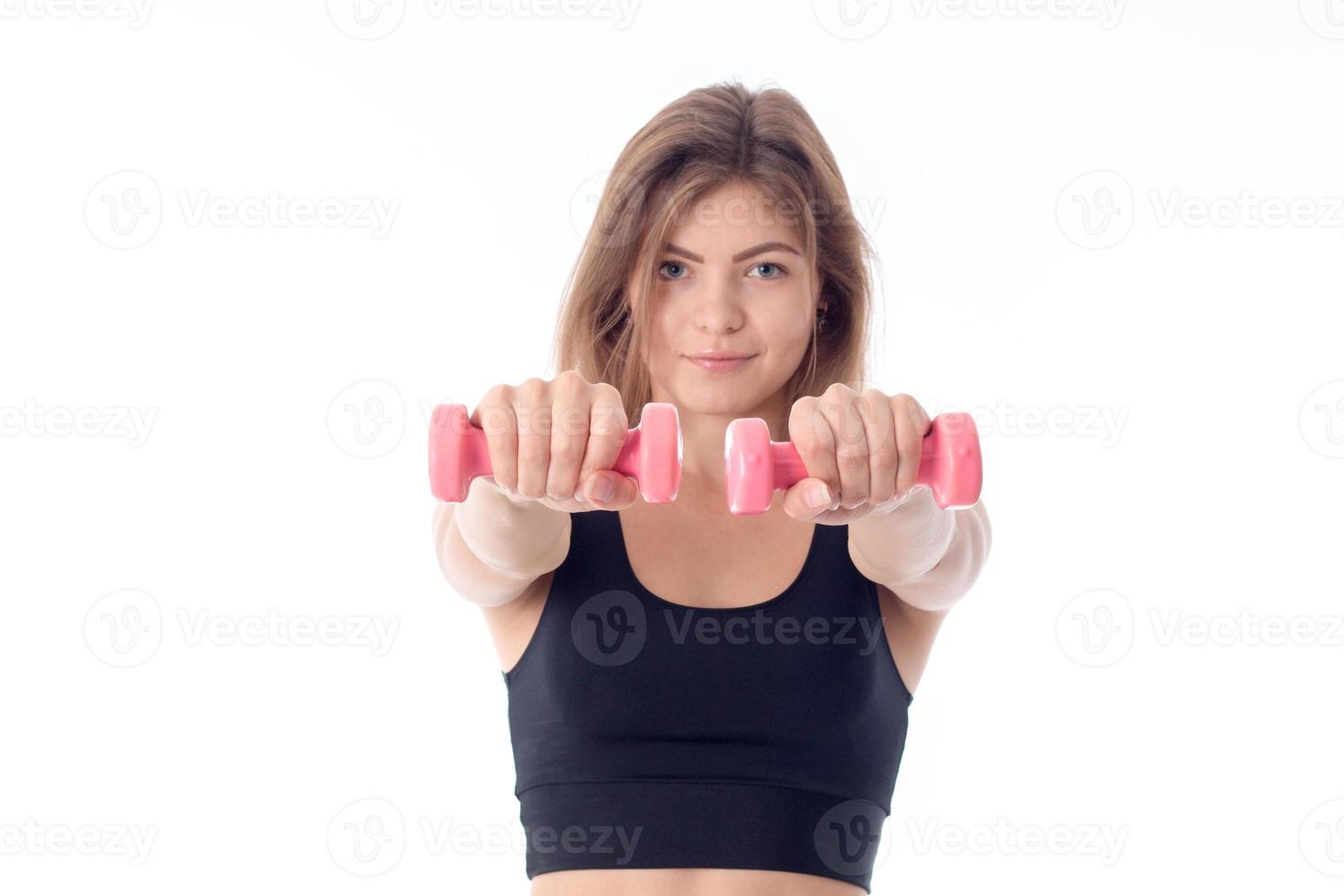 chica joven en un top deportivo negro sosteniendo pesas foto