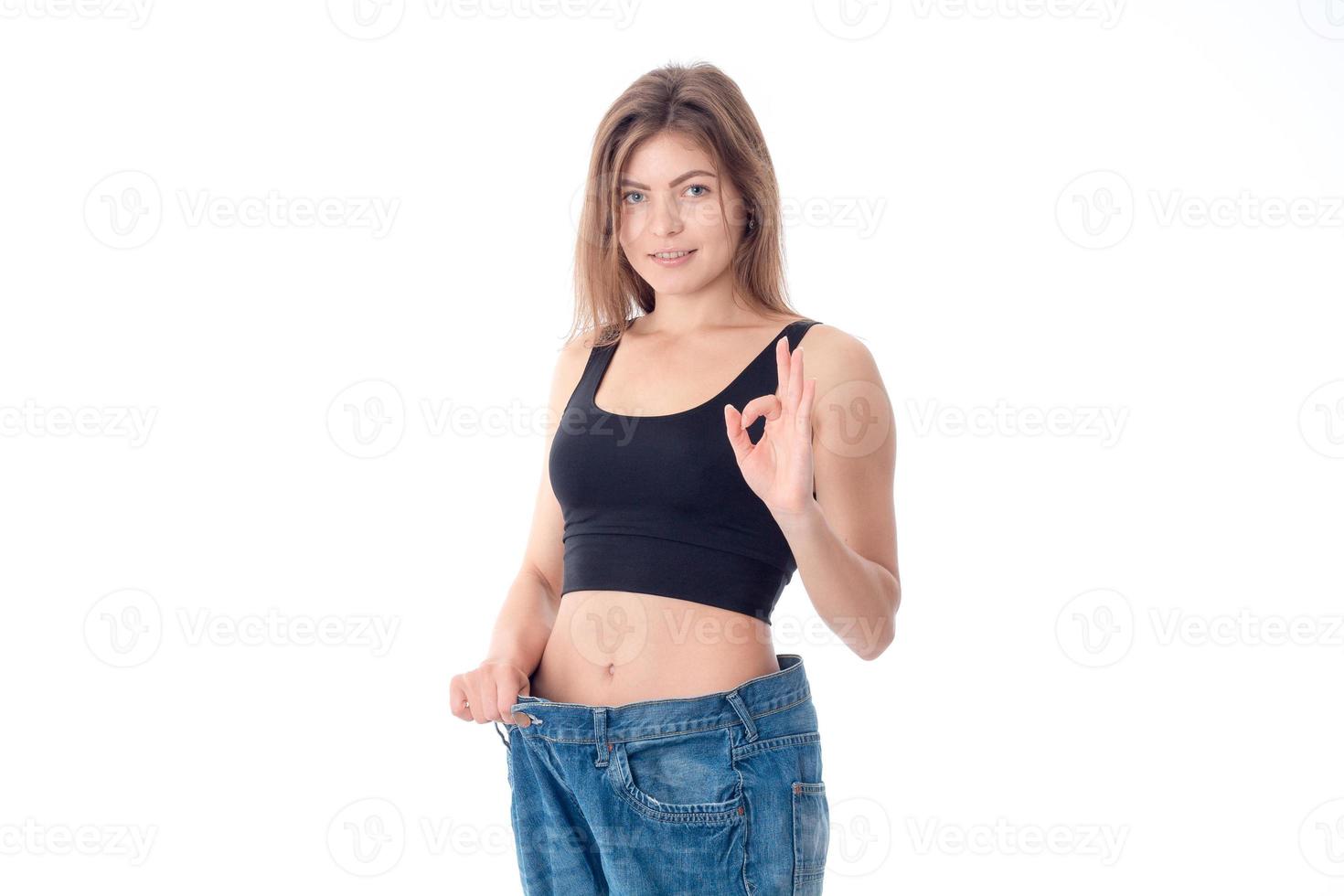 Slim girl in black top and the big jeans isolated on white background photo