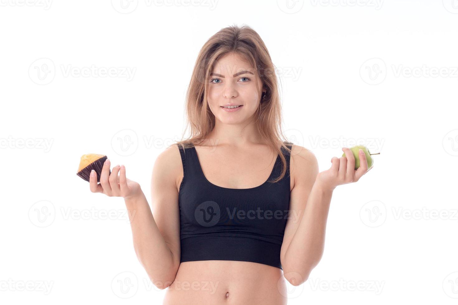 young girl in black top stands up straight and holding Apple  a cupcake is isolated on  white background photo