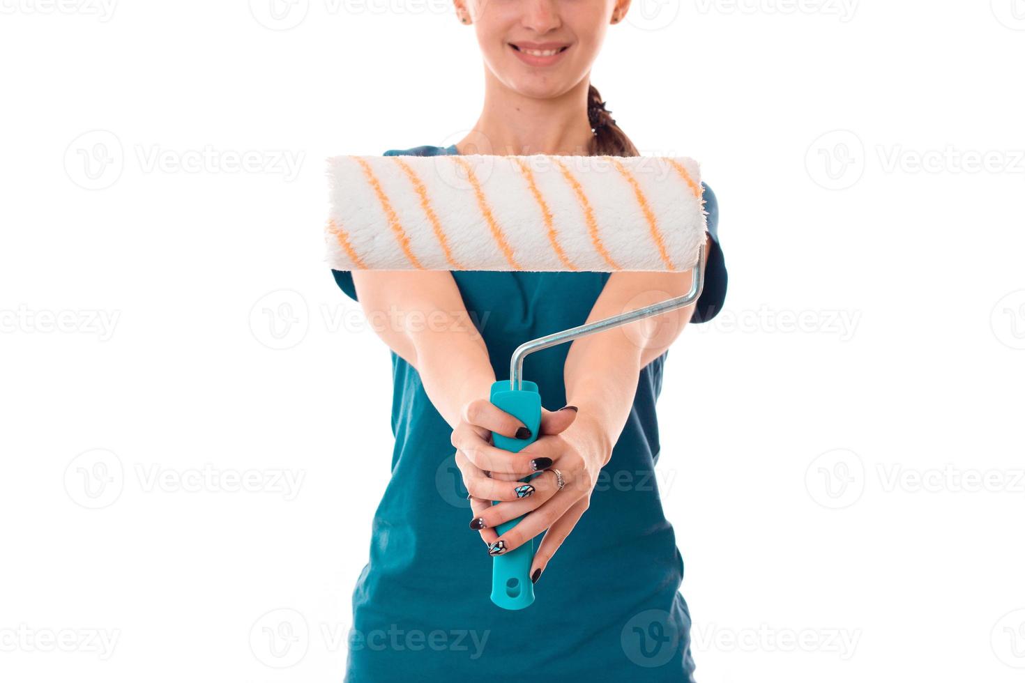 young builder girl in uniform makes renovation with paint roller in her hands isolated on white background photo