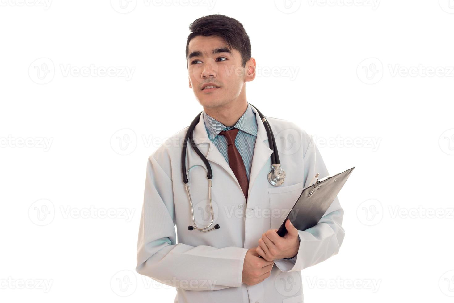 pretty elegant doctor in uniform with stethoscope smiling on camera with board in hands isolated on white background photo