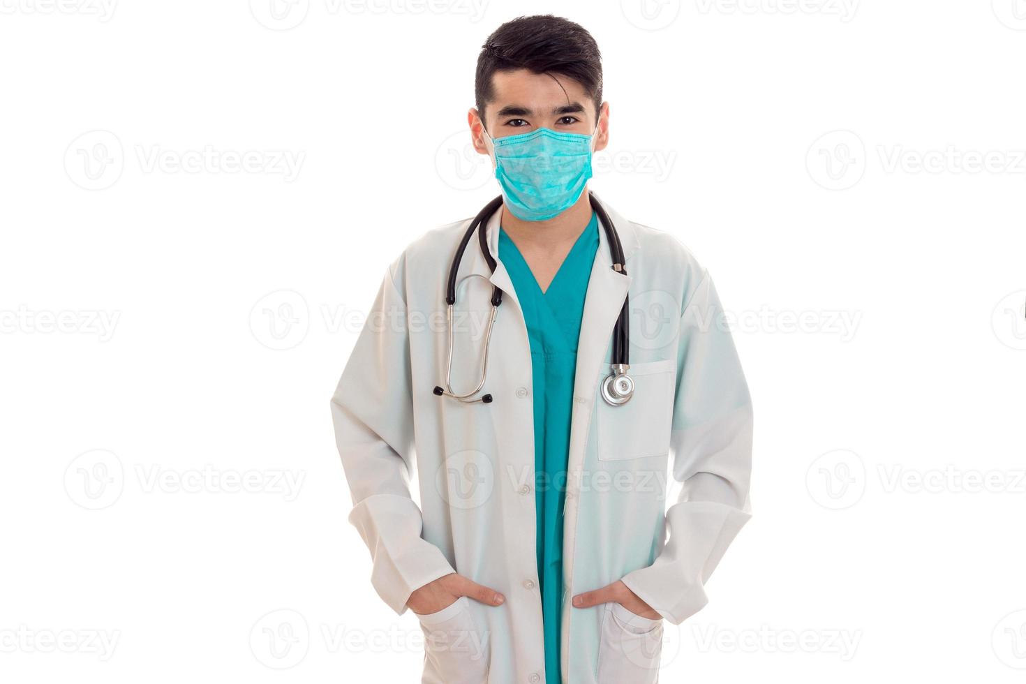 cute elegant doctor in blue uniform with stethoscope and mask posing and looking at the camera isolated on white background photo