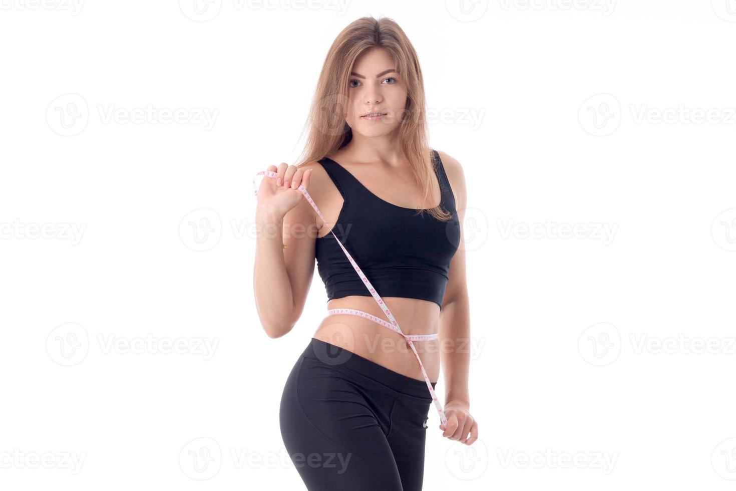 Pretty slim girl measures the volume of a tape measure around her waist photo