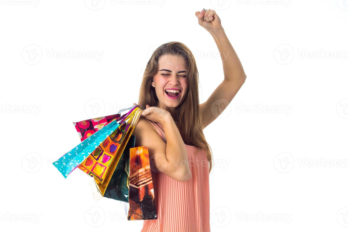 happy young girl raised her hand and keeps a lot of gift packages, isolated on white background photo