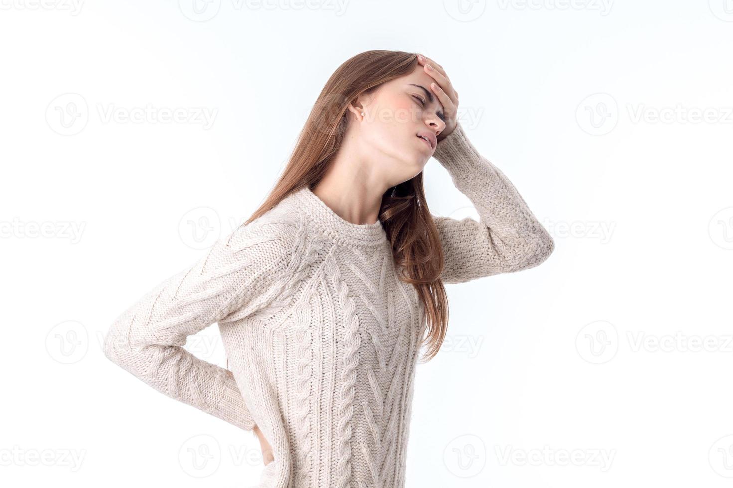girl in  sweater stands sideways put one hand on the side and the second  is held behind the head isolated  white background photo