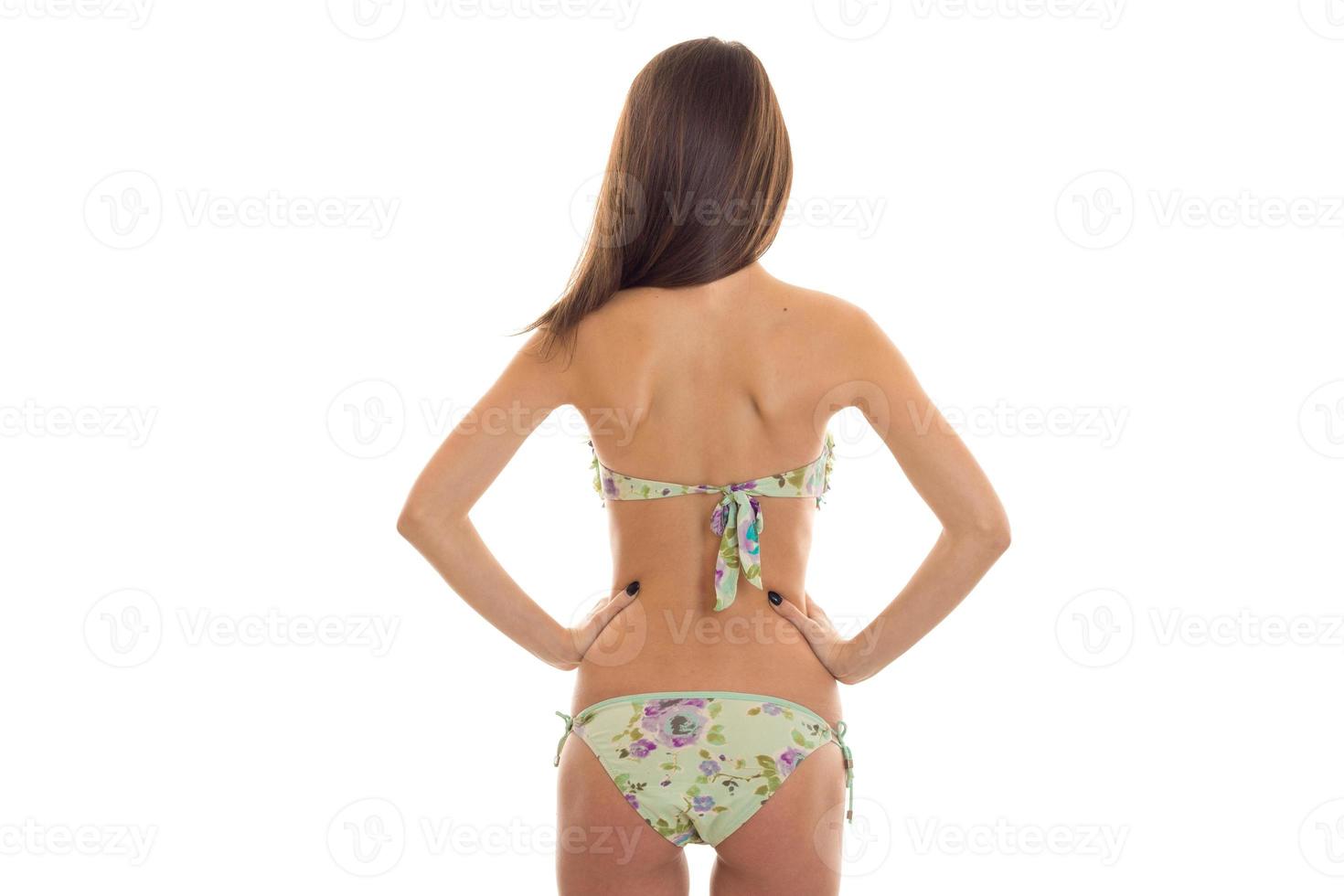 slim brunette woman with beautiful round buttocks in swimsuit with floral pattern posing from behind isolated on white background photo
