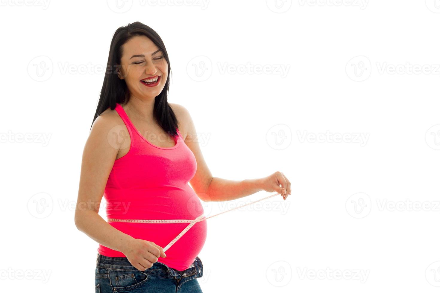 Funny brunette pregnant woman measure her belly with tape and laughing